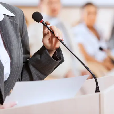 Hand holding microphone with audience in background