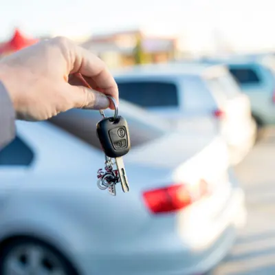 Hand holding keys in parking lot