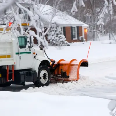 Snow plow and snow with house in background